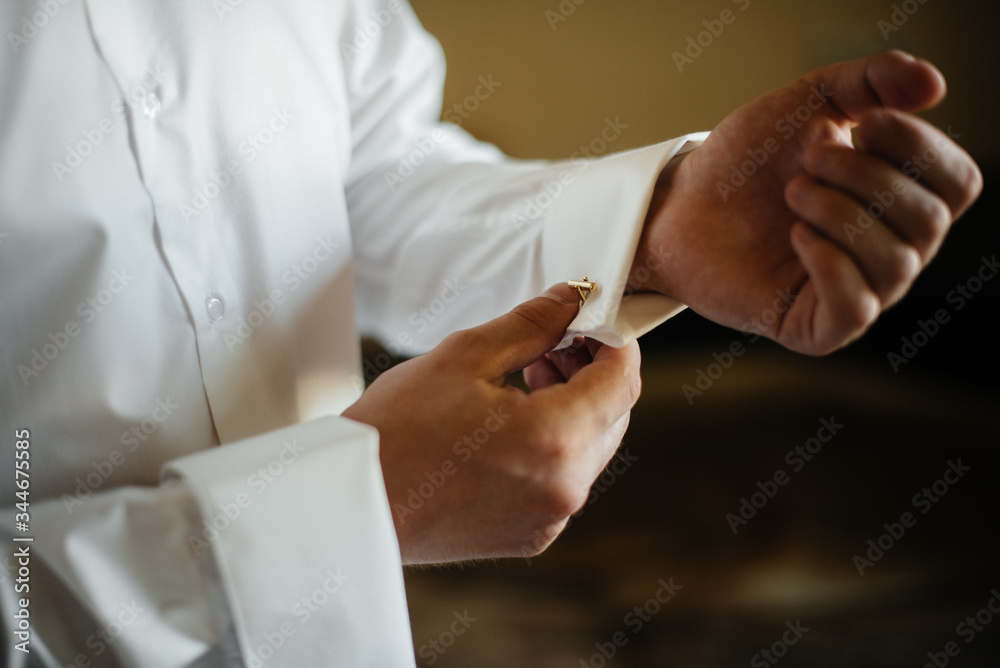 Stylish young man buttoning the cuff links on the sleeves. Style Stylish young man buttoning the cuff links on the sleeves. Style