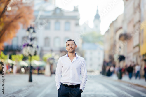 young man in shirt and glasses standing on city street
