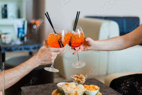 Women holding glasses of aperol spritz cocktails at cafe. Traditional Spritz aperitif.