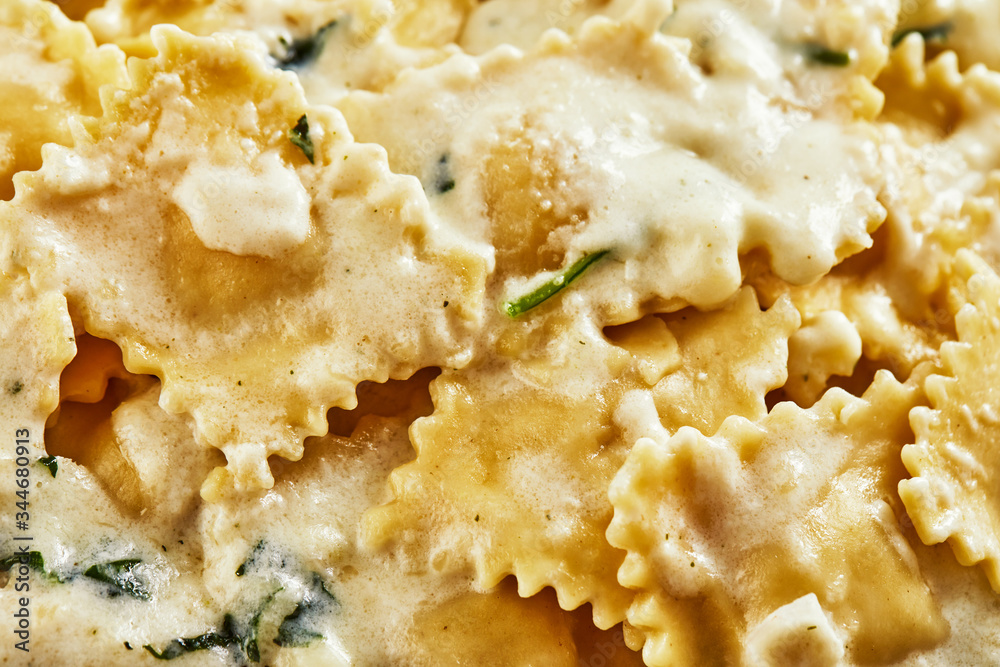 Tasty cooked ravioli with cream sauce, cherry tomatoes, sunflower oil and basil on a light wooden background. Tasty cooked ravioli with cream sauce, cherry tomatoes, sunflower oil and basil on a light wooden background.
