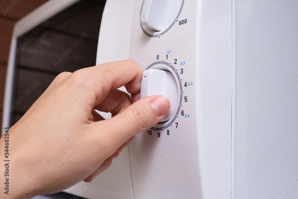 Woman hand turning on microwave oven in order to prepare, heat food for lunch or dinner, kitchen elecrtric appliances using concept Woman hand turning on microwave oven in order to prepare, heat food for lunch or dinner, kitchen elecrtric appliances using concept