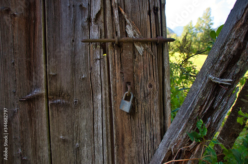 ein Riegel mit Vorhängeschloss am Tor einer verlassenen alten Scheune locked and lost