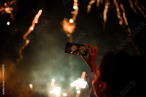 Hand of woman taking the photo to fireworks with the new smartphone. photo