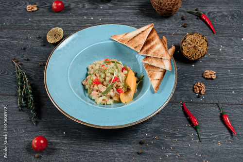 sresh salmon salad and toasted bread in blue plate on grey served table. traditional dish menu served in a restaurant photo