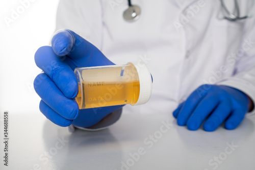 Doctor in white uniform are holding up a blank plastic bottle with yellow liquid inside. Urin sample test and vaccination concept. Drug abuse, covid-19 and sample illustration. photo