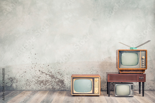 Canvas Print Retro cathode ray tube (CRT) monochrome television sets and classic wooden TV stand with outdated amplifier front concrete wall background