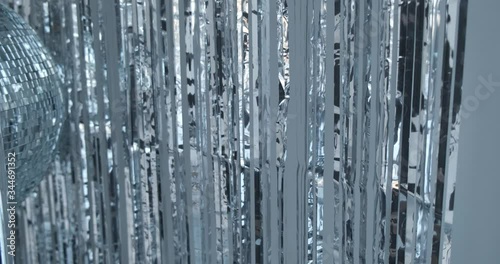 Camera moves along decorated part of stage, ball for parties in frame, foil on wall, reflections, rays, party decoration, abstract frame, overflows, eighties style party, side-to-side camera movement