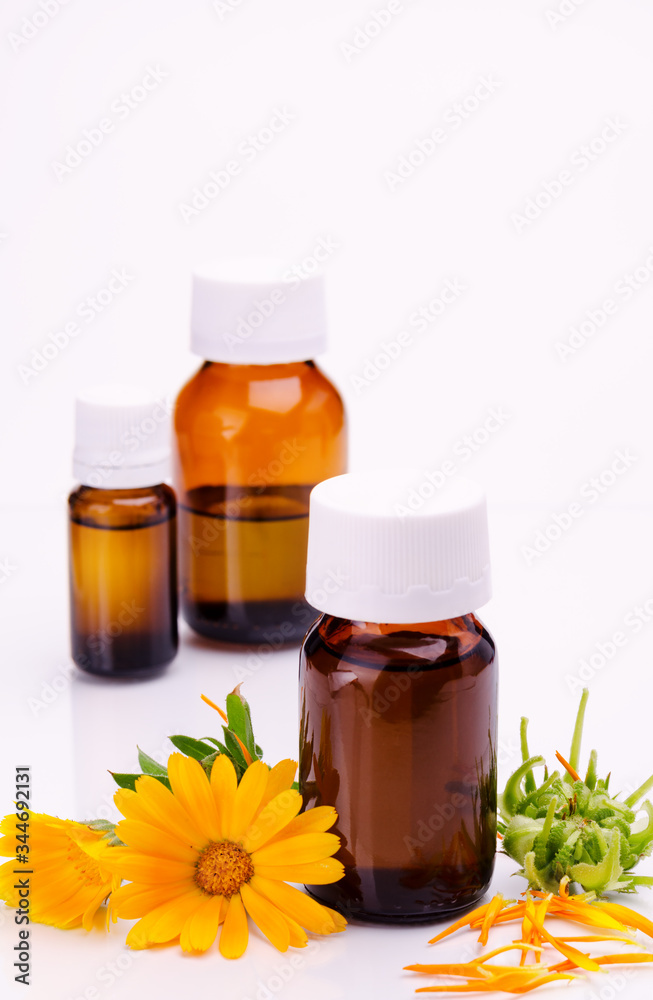 Dark cosmetic bottle of aromatic oil for herbal medicine with calendula flower isolated on white backdrop. Marigold extract. Dark cosmetic bottle of aromatic oil for herbal medicine with calendula flower isolated on white backdrop. Marigold extract.