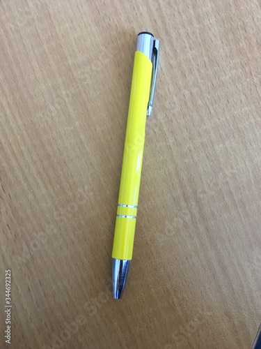 Żółty metalowy długopis leży na brązowym stole