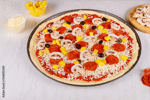 Raw unbaked pizza with pepperoni and mushroom.
