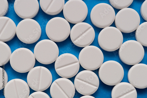 White round tablets on a blue background. Macro of white capsules on blue background.