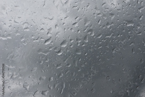 Close-up of raindrops on a car window against grey overcast sky