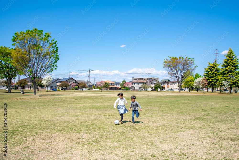 Fototapeta premium 青空の公園でサッカーをする子供
