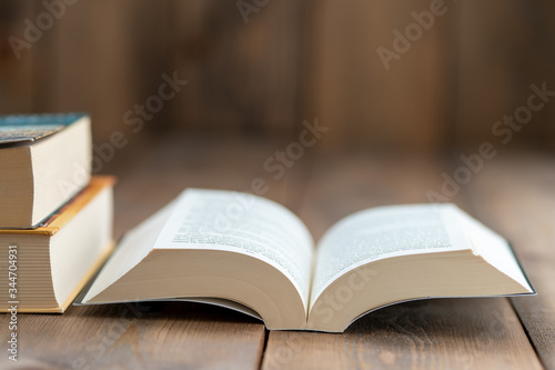 A hardback book opened for reading and two large books stacked on the right