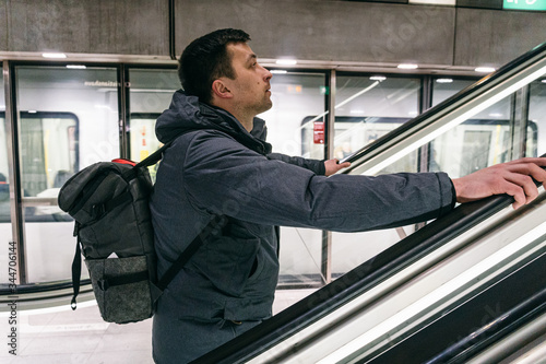 Caucasian male tourist with a backpack in the subway Copenhagen, Denmark. Caucasian man with a backpack up the escalator in the metro. Underground station in Copenhagen