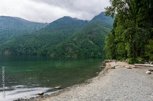 small beach at Chilliwack lake with high mountains and cloudy sky british columbia canada.