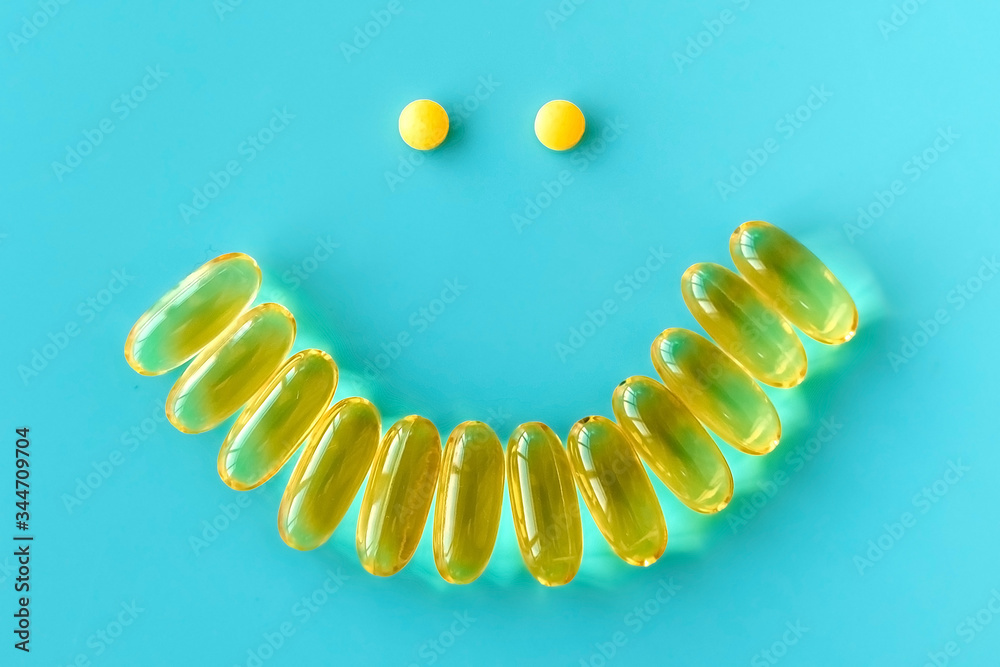 Obraz premium Smile from omega 3 capsules on blue background, positive from pills, the concept of good mood and recovery.