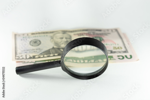 money dollars and euros through a magnifier. On white background