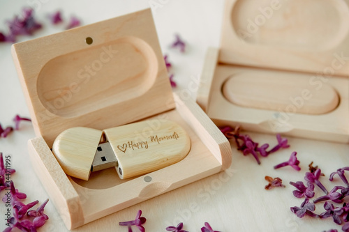 Fényképezés Wooden brown usb flash drives with boxes with the text Happy Moments with lilac petals on a white background, data storage, beautiful feedback to client