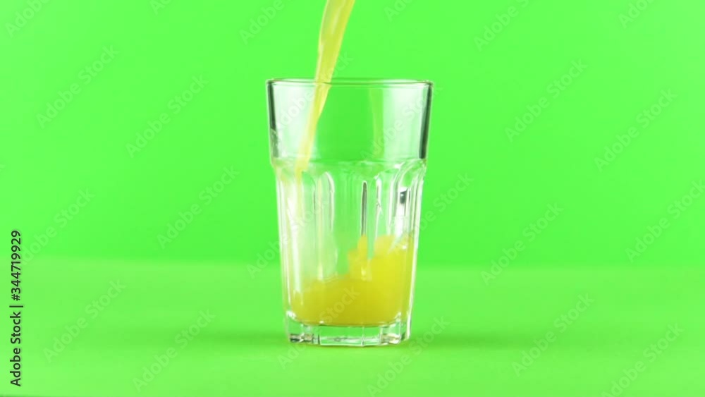 Juice pouring into glass isolated on light green background slow motion , vitamin and mineral juice healthy lifestyle Juice pouring into glass isolated on light green background slow motion , vitamin and mineral juice healthy lifestyle