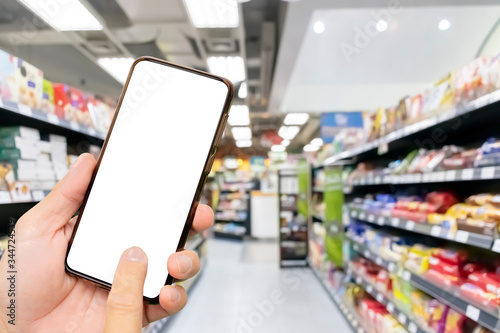 Touch screen smartphone in a hand, Blurred Supermarkets.