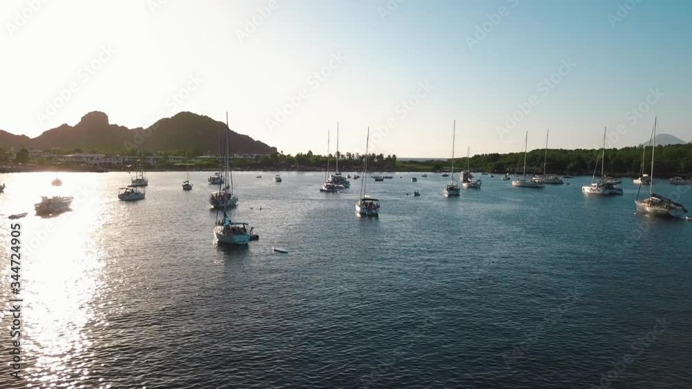 Aerial view on seashore of Lipari Island. Green trees and buildings. Mountains and sunrise. Yachts, catamarans and boats. Sicily, Italy Aerial view on seashore of Lipari Island. Green trees and buildings. Mountains and sunrise. Yachts, catamarans and boats. Sicily, Italy