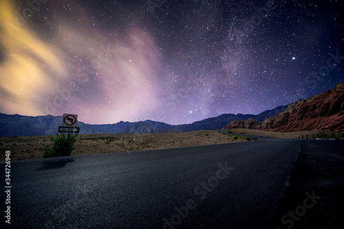 Red Rock Canyon in Las Vegas, Nevada, USA under a star lit sky glowing over the asphalt scenic byway.