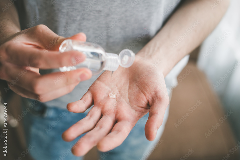 Fototapeta premium men using a small hand-held antibacterial hand sanitizer, coronavirus protection