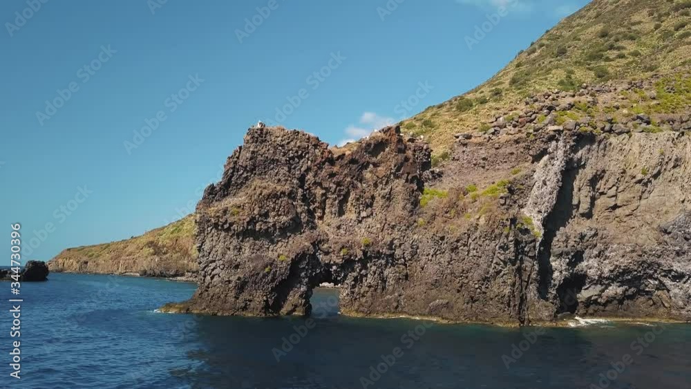 Aerial view on white sailing catamaran and rock with hole in the Mediterranean sea against Lipari Island. Sicily, Italy Aerial view on white sailing catamaran and rock with hole in the Mediterranean sea against Lipari Island. Sicily, Italy