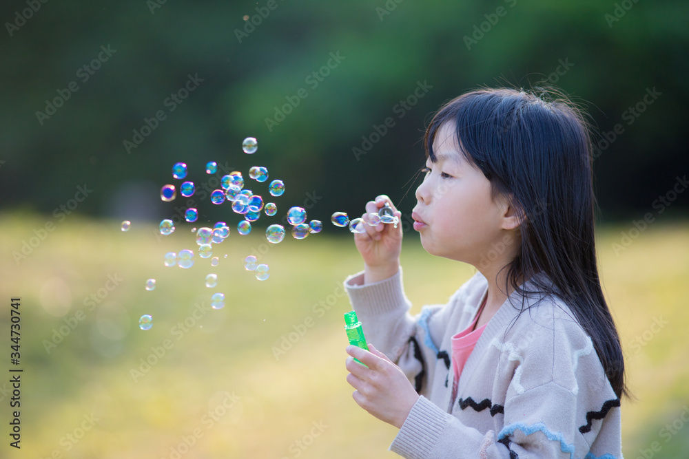初夏の公園でシャボン玉を遊んでいる子供