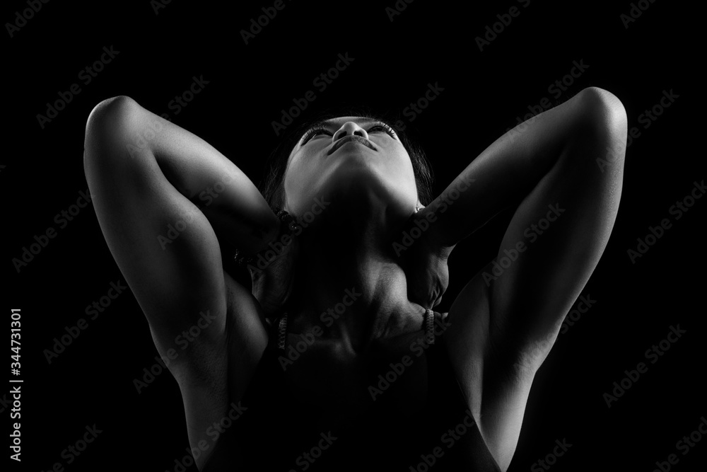 Fototapeta premium Black and white dark contrast photo of muscular arms of young fitness woman,