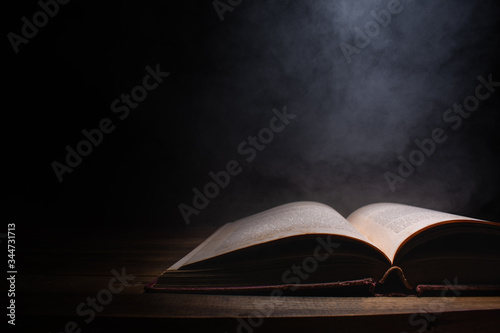 open a mysterious old book on wooden table, smoke float up from book