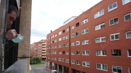 sick man covid-19 virus with mask peeking out the window using a smartphone