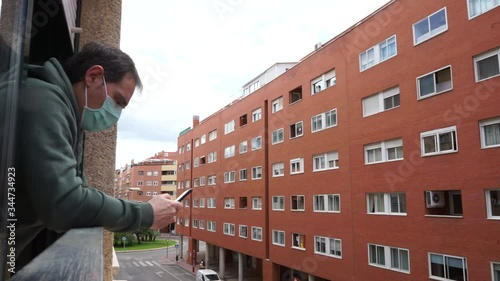 sick man covid-19 virus with mask peeking out the window using a smartphone