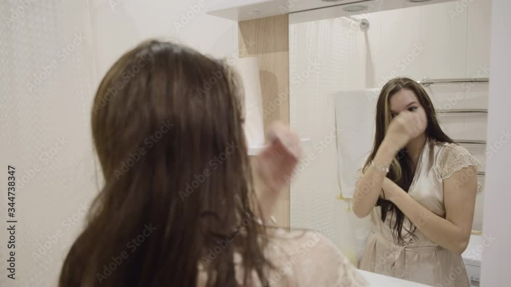 Young brunette girl with long dark hair in bright clothes is washing fun and brushing her teeth at home in the bathroom Young brunette girl with long dark hair in bright clothes is washing fun and brushing her teeth at home in the bathroom