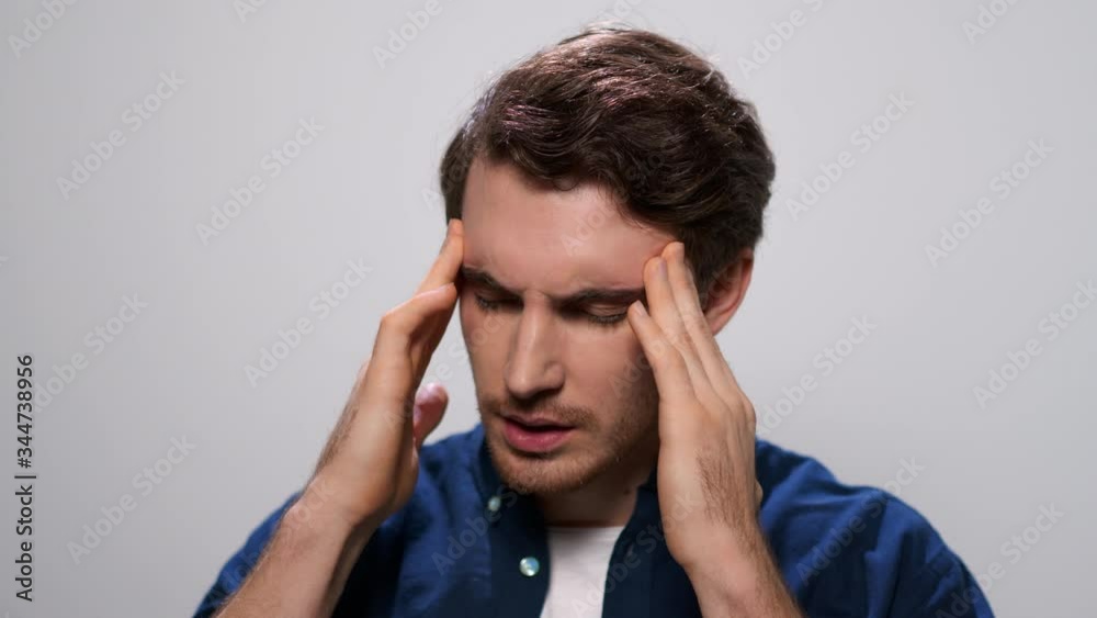 Man holding hands on head. Closeup tired guy having headache in studio Man holding hands on head. Closeup tired guy having headache in studio
