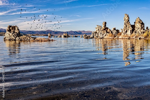 Beautiful shot of Tufa Towers with flock of birds flying above the water at Mono Lake, California photo