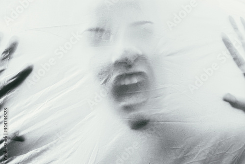 Beautiful female face through the fabric. Scary black and white background