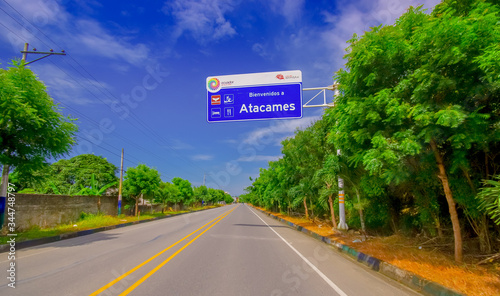 Esmeraldas, Ecuador - March 16, 2016: Paved road in the coast, with informative sign, surrounded with abundat vegetation in a sunny day in the Ecuadorian coasts
