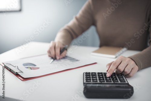 businesswoman working with data sheet on white desk with calculator, laptop, pad, smartphone at office look very busy. work from home concept