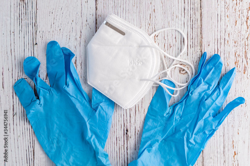 White commercial KN95 protective face mask and blue nitrile gloves on a white rustic background
 photo