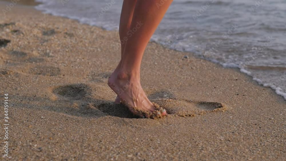 close up woman feet walking barefoot on beach at sunset leaving footprints in sand female tourist on summer vacation. close up woman feet walking barefoot on beach at sunset leaving footprints in sand female tourist on summer vacation.