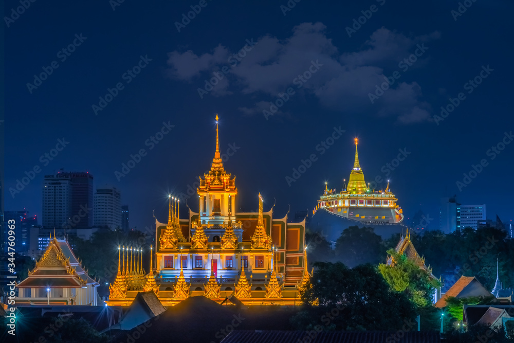 Naklejka premium Loha Prasat Wat Ratchanatda and Golden Mountain pagoda at night in Bangkok, Thailand.