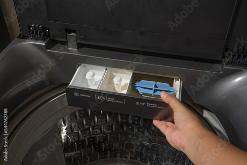 Top load washing machine detergent compartment opened by man hand. Close up,