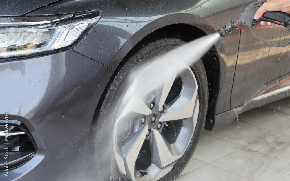 Closeup of grey car cleaning, washing by  high pressure water spraying.