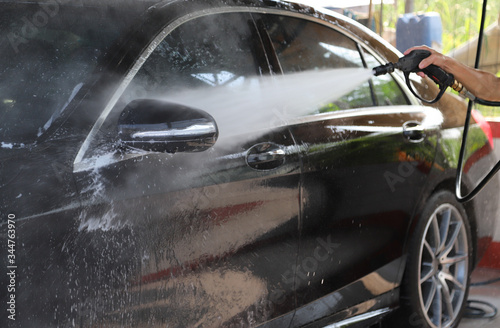 Closeup of black car cleaning, washing by high pressure water spraying to remove dust and dirty things.