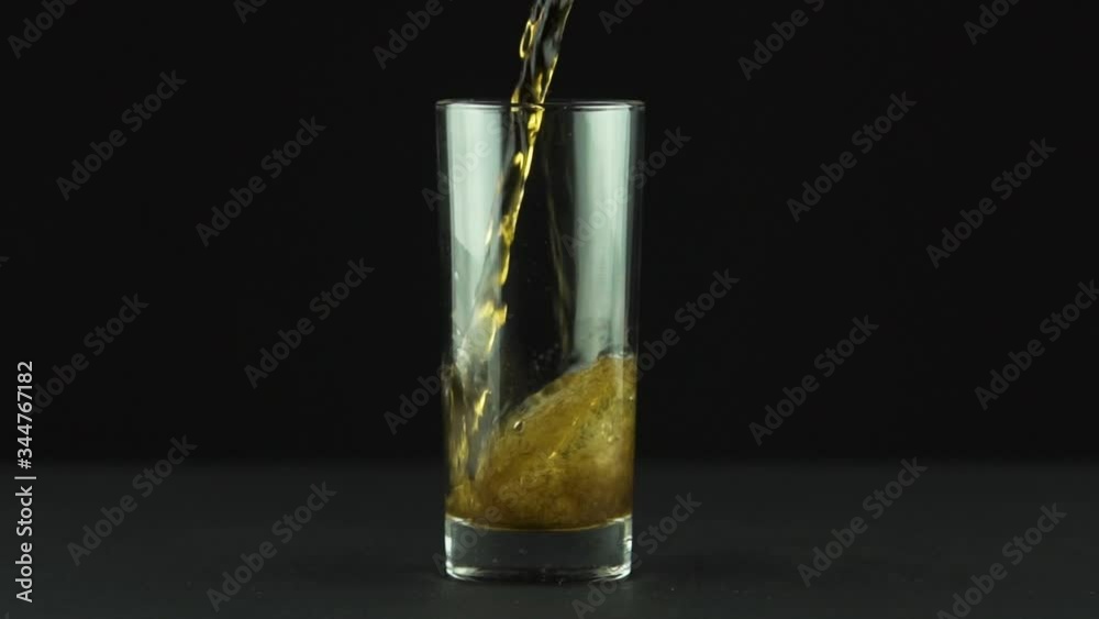 Cola is poured into glass full of bubbles and foam isolated on black background . Unhealthy brown carbonated sweet soda drink close up