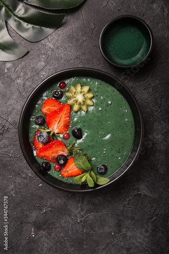 Colorful, healthy food. Acai smoothie bowl. Keto breakfast idea. Fruit curd smoothie, acai. Breakfast with green spirulina, strawberry, chia, kiwi in black plate photo