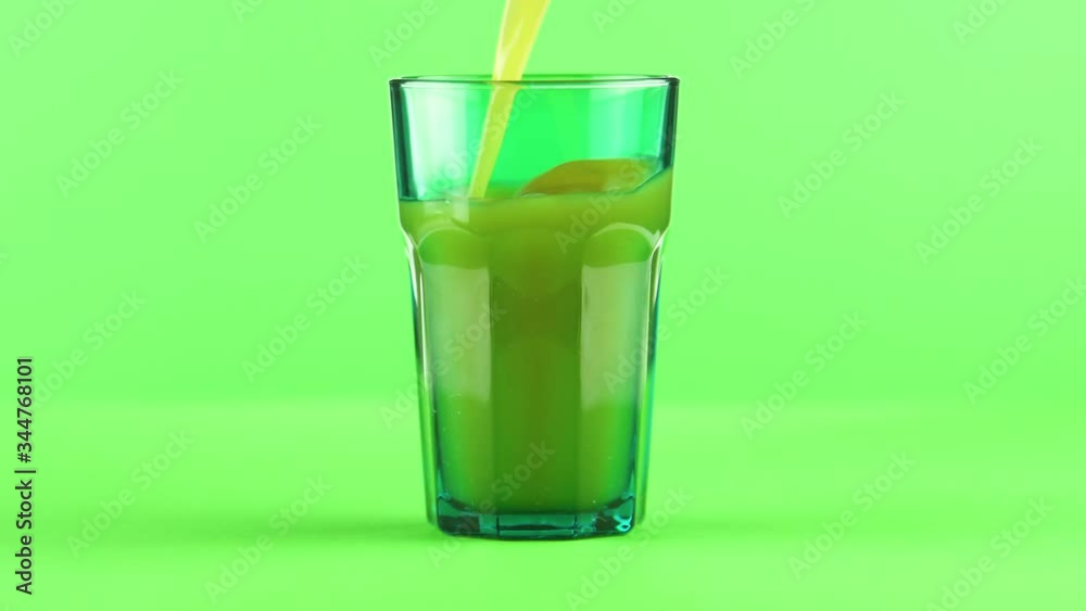 Juice pouring into green faceted glass isolated on light green background , vitamin and mineral juice healthy lifestyle Juice pouring into green faceted glass isolated on light green background , vitamin and mineral juice healthy lifestyle