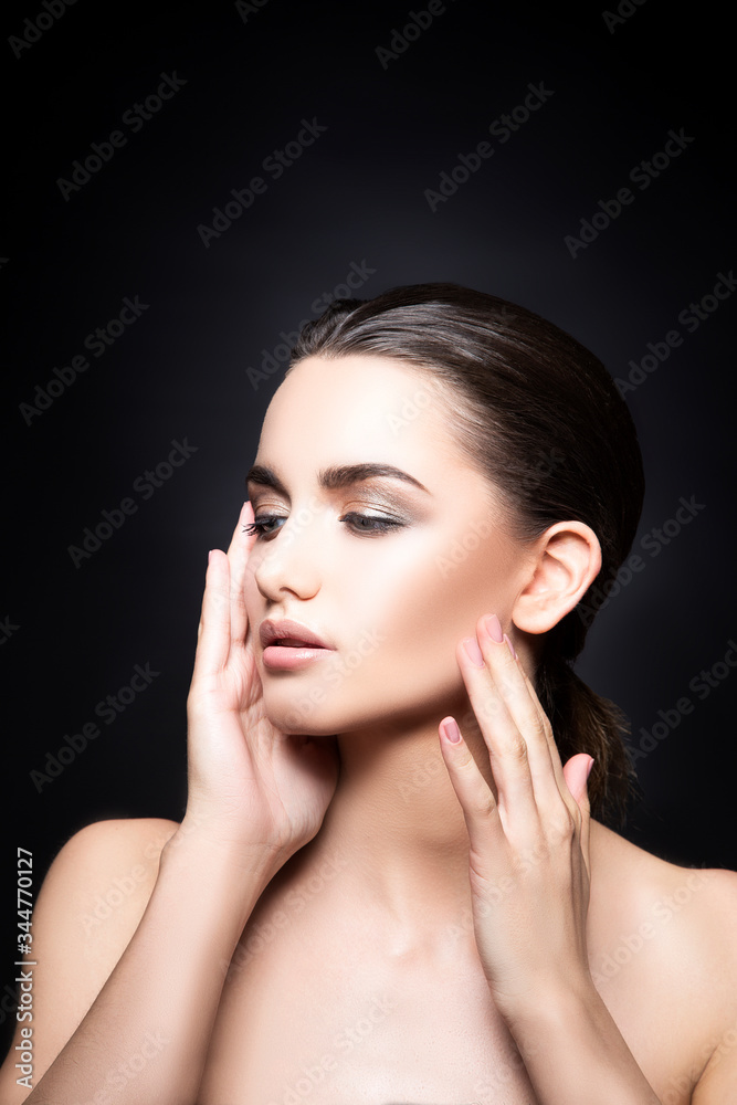 Beauty face of young caucasian model girl. Eye shadow make-up, hands near face. Perfect skin. Skin care health concept. Black background. Copy space Beauty face of young caucasian model girl. Eye shadow make-up, hands near face. Perfect skin. Skin care health concept. Black background. Copy space